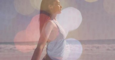 Rüzgarı motive eden kadın kollarını açıyor ve kıyı şeridinde parlayan bokeh ile sağlığına kavuşmak için nefes alıyor. Dinginlik, rahatlama, farkındalık, doğa, aydınlanma, uyum, açık hava