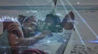 Kumsaldaki hamağa yerleşen çift dijital veri eşleştirme modunu teknolojiyle örtüyor. Romantizm, rahatlama, bağlantı, dinginlik, açık hava, boş zaman, fütüristik