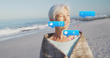 Sahilde şallı bir kadın yükselişteki bağlılığını gösteren sosyal medya tepkilerine neden oluyor. Son sınıf, açık hava, plaj, rahatlama, sıcaklık, bağlantı, huzur.