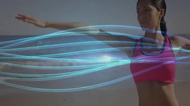 Kadın kollarını kaldırıp kumsalda spor yaparken ışık izlerini aktifleştiriyor. Sağlık, sağlık, egzersiz, canlılık, hareket, dinginlik, açık hava