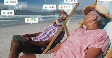 Üst düzey çiftler plaj sandalyelerinde dinleniyor, telefonları dinliyor ve yüzen sosyal medya ölçümlerini izliyorlar. Boş zaman, sükunet, bağlantı, deniz kenarı, emeklilik, manzara, uyum.