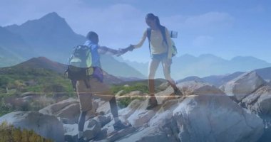 Sırt çantalı iki yürüyüşçü aşağı iniyor ve erkek yanaşırken el desteği teklif ediyorlar. Macera, takım çalışması, keşif, engebeli, zafer, dostluk, açık hava