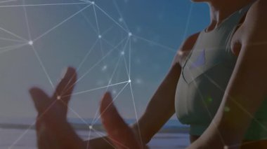 Kumlu sahil şeridinde kollarını kaldıran bir kadın ellerin etrafında ışıldayan bir ağ oluşturarak farkındalığı yönlendiriyor. Zen, sükunet, holografik, dijital, dinginlik, refah, maneviyat