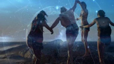 Gün batımı parıltısı, dört kadının el ele tutuşup titreşimli teknoloji ağıyla taş sektirmesi. Bağlantı, arkadaşlık, macera, canlılık, sağlık, dijital, açık hava