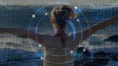 Kayalık sahil alacakaranlığında duruyor, kollarını kaldırıp verileri senkronize ederek teknolojik HUD 'u kadının etrafında çeviriyor. Gelecek, teknoloji, dijital, yenilik, açık hava, dinamik, dinamik