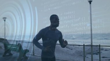 Yetişkin bir erkek koşucu şafak vakti deniz kenarında koşuya başlıyor. Kaplama izleme kondisyonunu etkinleştiriyor. Atletik, teknoloji, performans, sağlık, açık hava, enerji, spor