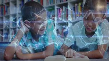 Okulun kütüphanesinde iki çocuk dijital dalga nabzı atarken yüksek sesle okuma ve mesaj izliyor. Eğitim, okur yazarlık, teknoloji, işbirliği, gençlik, odaklanma, öğrenme