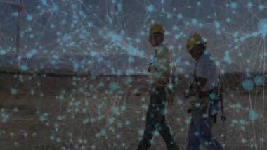 Teknisyenler rüzgar türbinine doğru yürürken mavi düğümler veri akışını haritalıyor. Enerji, yenilik, bağlantı, teknoloji, sürdürülebilirlik, otomasyon, kesinlik