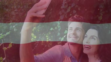 Akıllı telefonu yukarı doğru uzatan bir adam, öne eğilen bir kadın, kafaları hizalayan, sarmaşıkların arasında teknik selfie çeken bir adam. Romantizm, bağlantı, açık hava, yaşam tarzı, canlı, arkadaşlık, doğa