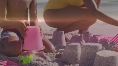 Çocuk kürek kullanıyor ve annesi turizm için kuleleri dökerken pembe kovaya atlamaya başlıyor. Kumsal, kumdan kale, aile, açık hava, güneşli, dinlenme, yaz