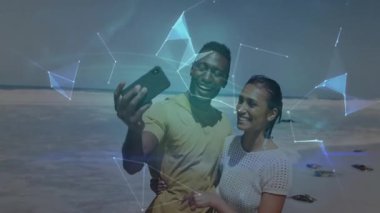 Kumsalda akıllı telefon kaldıran ve haritayı keşfetmek için dönen hologram dünyasını çalıştıran çift. Romantik, kıyı, geleceksel, etkileşimli, bağlantı, macera, teknoloji