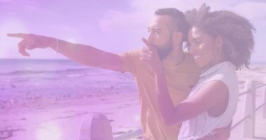 Sahil korkuluklarına yaklaşan gezgin çift görmek için duraklıyor, adam denizi işaret ediyor, kadın kolunu kaldırıyor. Romantik, kıyı, bağlantı, mutluluk, manzara, eğlence, canlı