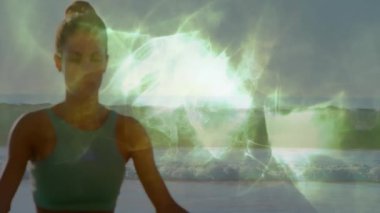 Sahilde oturmuş meditasyon yapan bir kadın yavaşça yeşil enerji aurasını canlandırıyor. Meditasyon, sükunet, refah, maneviyat, doğa, dinginlik, farkındalık.