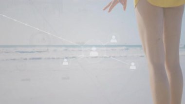 Sahil şeridinde duran bir kadın ağ oluşturmaya başlıyor ve gökyüzü ile okyanus arasındaki teknolojik bağlantıyı gösteriyor. Deniz kenarı, dijital, bağlantı, sükunet, çevre, yenilik, huzur