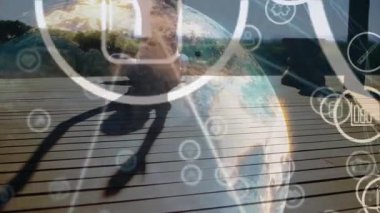 Teras minderinde katlanan kadın, sağIık için sürüklenen ikonlar ve titreşen dijital küreyi oluşturan ikonlar. Meditasyon, farkındalık, teknoloji, yenilik, dinginlik, manzara, sağlıklı yaşam tarzı