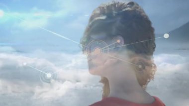 Teknoloji demosunda duran bir kadın kulak sensörünü etkinleştiriyor ve ağ düğümlerini denizden yansıtıyor. Deniz kenarı, bağlantı, fütürizm, teknoloji, refah, yenilik, ağ