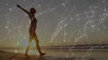 Gün batımında sahilde dikilen kadın, teknoloji ağı yoğunlaşırken havayı kucaklıyor. Huzur, siluet, yansıtıcı, fütüristik, dinginlik, hareket, manzara