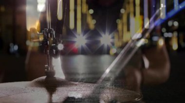 Şehir ışıkları müzik ritmiyle titreşirken davulcu sopasını kaldırıyor ve zile basıyor. Müzik, performans, gece hayatı, şehir, ritim, enerji, sahne