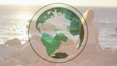 Yeşil küre dönüyor, kayalık sahil günbatımında kayboluyor meditasyon yapan bir kadının sağlığını arttırdığını gösteriyor. Toprak, sükunet, farkındalık, doğa, dinginlik, rahatlama, meditasyon