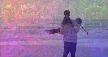 Anne çocuğu pembe yüzme halkasıyla sığ dalgalarda kaldırıyor ve sağlığı için döndürüyor. Aile, kaynaşma, açık hava, eğlence, neşeli, dingin, enerjik