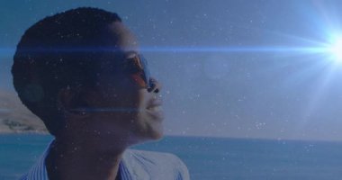 Kafasını güneşe doğru eğen bir kadın mavi mercek gibi parıldıyor ve plaj gözlüğü vitrinini ortaya çıkarıyor. Portre, sükunet, moda, açık hava, doğal, canlı, iyimser