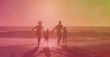 Siluetli aile gün batımında dalgalı bir şekilde sörf yapmadan önce el ele tutuşup sallanıyor. Aile, birliktelik, sahil, gün batımı, siluetler, ahenk, açık hava