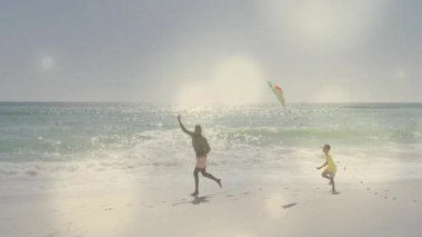 Baba açık havada eğlenmek için koşuyor ve uçurtma sallıyor. Oğul da kuyruk kovalıyor. Açık hava, boş zaman, aktivite, neşeli, güneşli, enerjik, macera