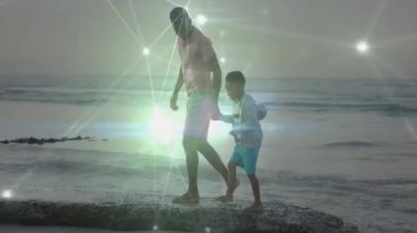 Kayalık çıkıntıya adım attığında, baba sırt çantalı çocuğa rehberlik eder sağlık için dalgaların üzerinde dengede durur. Macera, bağ, aile, açık hava, keşif, sükunet, vahşi yaşam