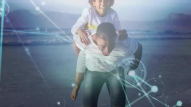 Oğlunu taşıyan bir adam dijital ağ hatları ve titreşimli kum kabuğu teknolojisi boyunca yürüyor. Aile, bağ, bağlantı, yenilik, açık hava, rahatlık, sıcaklık.