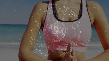 Sağlık uzmanı okyanus kıyısında el sıkışıyor ve dijital küreyi etkinleştiriyor ve pembe minder üzerinde meditasyon yapıyor. Meditasyon, farkındalık, sükunet, dijital, hologram, fitness, rahatlama