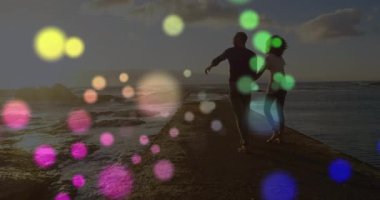 Gün batımında el ele tutuşan ve iskelede yürüyen küreler sürüklenirken güneşi gösteren çift. Romantik, dinginlik, macera, minimalist, rüya gibi, manzara, bağlantı