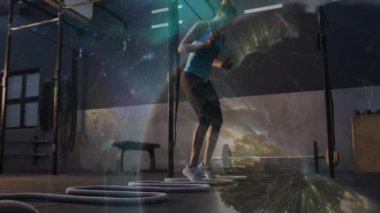 Kadın halkalara basarak çeviklik için 60 santimlik atlayışlar yapıyor kozmik bir şekilde spor salonunu kaplıyor. Fitness, atletizm, dinamik, modern, güç, eğitim, rekabet