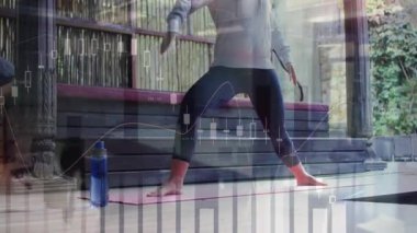 Yoga minderine basan bir kadın finansal tabloları ortaya çıkarıyor ve Warrior II 'yi pazar görüşü için tutuyor. Sağlık, farkındalık, açık hava, fitness, sükunet, sağlık, dijital