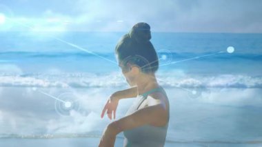 Dişi sporcu gövdesini döndürürken sağ omzunu esnetiyor ve zindelik arayüzünde kayboluyor. Açık hava, fitness, teknoloji, bağlantı, sağlık, görselleştirme, manzara