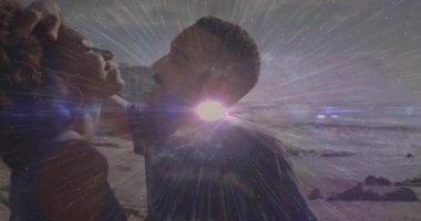 Plajda öpüşen çift, mercek darbeleri gibi sevgisini ifade eden saç tokasını kaldıran adamla öpüşüyor. Romantizm, samimiyet, günbatımı, dalgalar, şefkat, bağlantı, sükunet