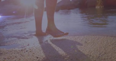 Ağırlığı sol ayağa kaydıran çıplak ayaklı adam sığ okyanus dalgalarına sağlık rutini için adım atıyor. Doğa, rahatlama, sağIık, farkındalık, kıyı şeridi, sükunet, yalınayak