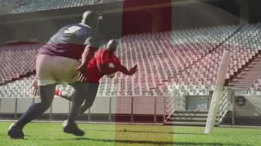 Kırmızılı ragbi oyuncusu gol atmak için koşuyor. Gri-mavi defans oyuncusu topu tutarak hücum ediyor. Sporcular, yarışma, yoğunluk, çeviklik, spor, aksiyon, stadyum