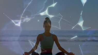 Yoga pratisyeni plajda meditasyon yapıyor, dijital çizgiler gökyüzünde sürükleniyor sağlık için holografik küre oluşturuyor. Meditasyon, dinginlik, maneviyat, fütüristik, sağlık, sükunet, farkındalık.
