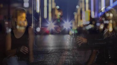 Üç arkadaş sohbet ediyor, konukseverlik barında bira kaldırıyor, neon farlar gece hayatını destekliyor. Sosyalleşme, gece hayatı, yoldaşlık, şehirli, enerjik, akşam, kutlama