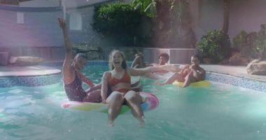 Kollarını kaldıran kadınlar su sıçratmaya başlar, arkadaşları çörek ve tüp üzerinde kürek çeker yaşam havuzunda yüzer. Boş zaman, rahatlama, eğlence, canlı, açık hava, yaz, sosyal...