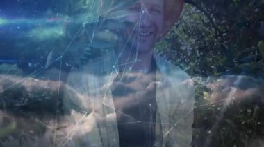 Etrafındaki bulut ağları çökerken şapka takan bir adam tarımsal verileri canlandırıyor. Doğa, teknoloji, sürdürülebilirlik, yenilik, tarım, uyum, dijital