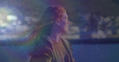 Parlak ışık yansıtıcı lens, gökkuşağı ve ışıltı. Bu arada kadın teknolojide deniz kenarındaki ufuk çizgisine bakıyor. Sinematik, kentsel, yansıtıcı, ortam, atmosferik, karamsar, düşünceli