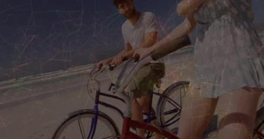 Kadın okyanusa doğru el sallıyor, adam kafa sallıyor, ikisi de güneşli sahil boyunca bisiklet sürüyor. Sahil şeridi, boş zaman, yaz, açık hava, arkadaşlık, terapi, hayat dolu