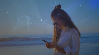 Sunset Beach 'te akıllı telefonları dinleyen bir kadın teknik demo için yörüngede ağ şemaları oluşturuyor. Fütürist, dijital, soyut, yenilik, bağlantı, sakin, zarif