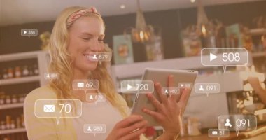 Kafede tablet kullanan bir kadın yüzen bildirim simgeleri görüyor ve sosyal medya bağlantılarını takip ediyor. Teknoloji, katılım, dijital, iletişim, modern, yaşam tarzı, yenilik.