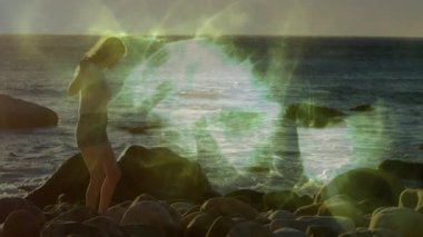 Bir kadın altın saat yolculuğunda kayalık kıyı şeridinde gezinirken ekin üstünü güvenli bir şekilde ayarlıyor. Sahil, sahil, macera, doğa, dinginlik, keşif, manzara