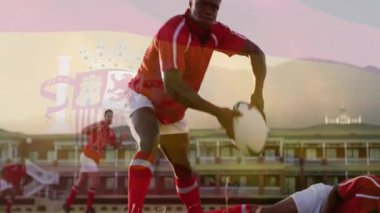 Kırmızı formalı ragbi oyuncusu, gün batımında topu sırtından alıyor ve destek için animasyon pası veriyor. Atletik, takım çalışması, açık hava, dayanıklılık, rekabet, aksiyon, spor