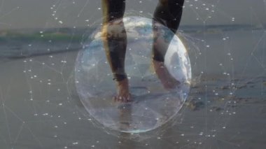 Sörf yapan bir adam, rüzgar sörfü platformunu denize doğru taşırken teknolojik küre kaplamasını başlatıyor. Macera, keşif, bağlantı, yenilik, açık hava, teknoloji, dayanıklılık