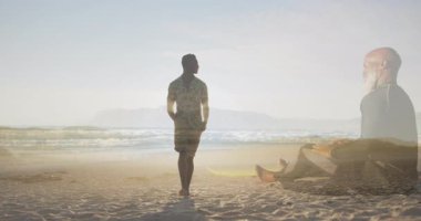 Yetişkin bir adam gün doğumuna doğru yürürken aynı zamanda sağlık için meditasyon yapan yaşlı bir sörfçü olarak siluet yaratıyor. Siluet, gündoğumu, plaj, meditasyon, sahil, sükunet, şafak