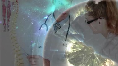 Erkek doktor, omurgasını hareketlendirerek dünyayı aktifleştiriyor ve meslektaşı da ağ tıbbi eğitimini izliyor. Tıbbi, eğitim, teknoloji, yenilik, işbirliği, anatomi, araştırma